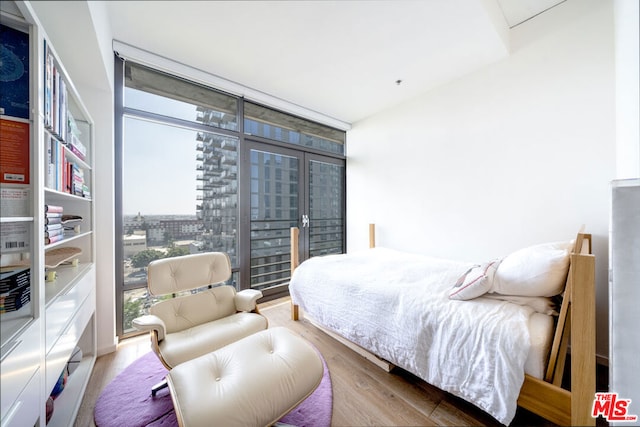 bedroom with multiple windows, french doors, floor to ceiling windows, and light wood-type flooring