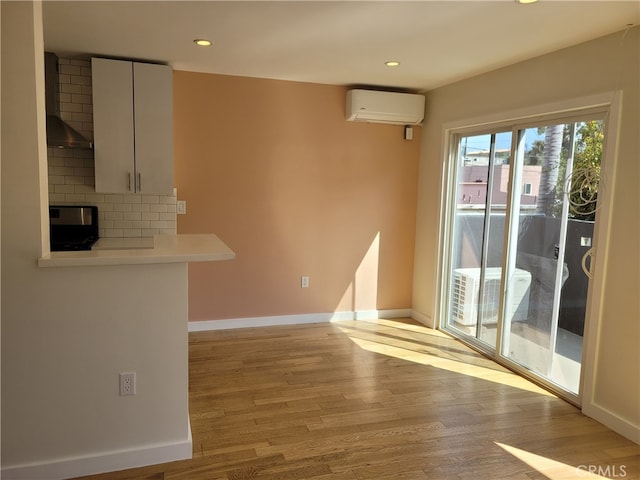 interior space featuring a fireplace, light hardwood / wood-style flooring, and a wall mounted air conditioner