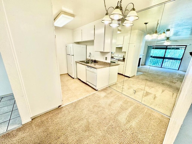 kitchen featuring white appliances, ceiling fan with notable chandelier, sink, light colored carpet, and white cabinetry