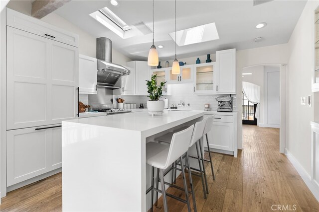 1165 Noria St, Laguna Beach, CA 92651 - kitchen with a skylight, ventilation hood, white cabinetry, a breakfast bar area, and recessed lighting