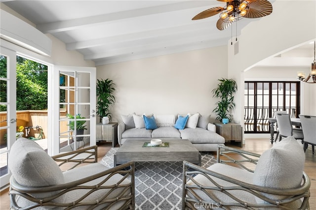 living room featuring ceiling fan with notable chandelier, vaulted ceiling with beams, and hardwood / wood-style flooring