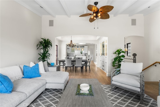 living room with hardwood / wood-style floors, ceiling fan with notable chandelier, and beam ceiling