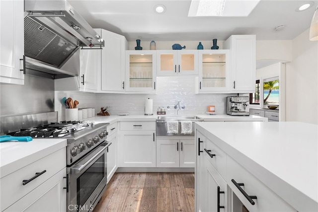 kitchen with white cabinets, light wood-type flooring, high end stove, and sink