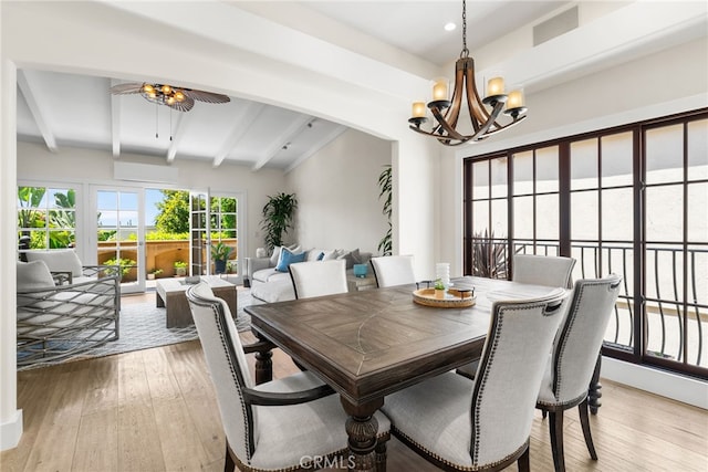 dining space featuring beam ceiling, an AC wall unit, ceiling fan with notable chandelier, and light wood-type flooring