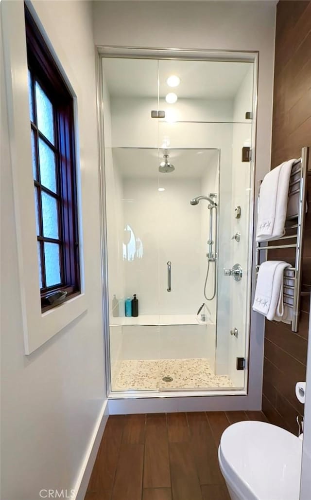 bathroom featuring toilet and a shower with shower door