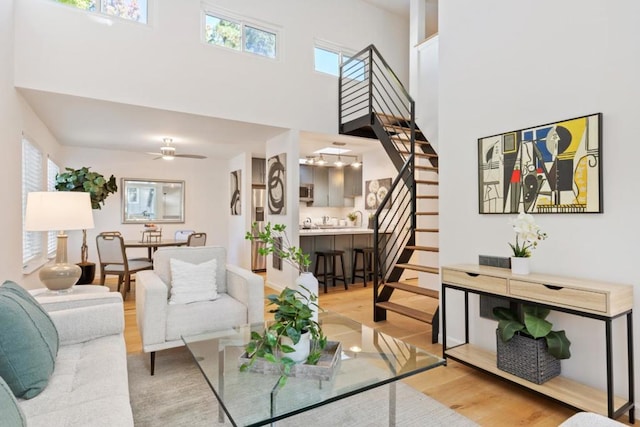 living room featuring ceiling fan, a high ceiling, wood-type flooring, and a healthy amount of sunlight