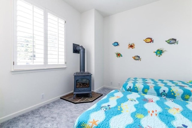 carpeted bedroom featuring a wood stove and multiple windows