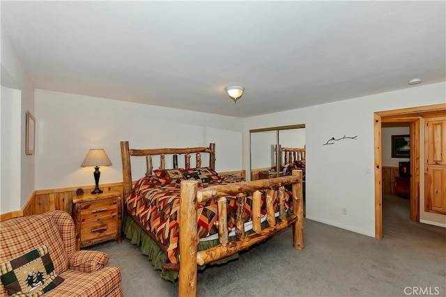 carpeted bedroom with a closet and wooden walls