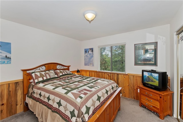 bedroom featuring wood walls and light colored carpet