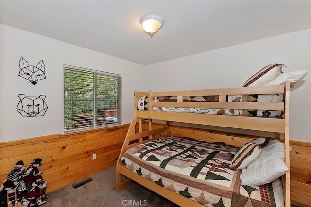 carpeted bedroom featuring wooden walls