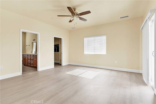 unfurnished bedroom featuring a spacious closet, multiple windows, light hardwood / wood-style floors, and ensuite bathroom