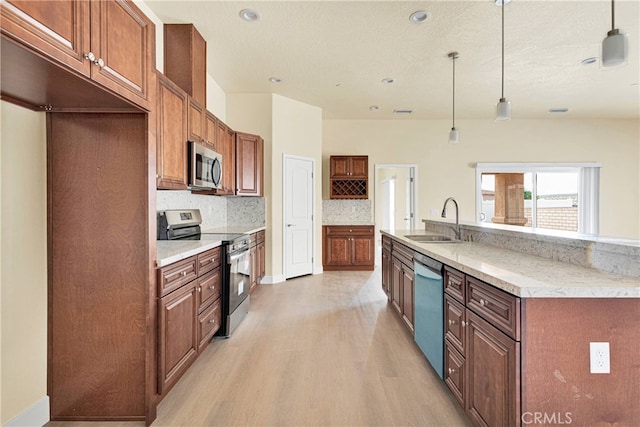 kitchen featuring light hardwood / wood-style flooring, appliances with stainless steel finishes, light stone countertops, and decorative light fixtures