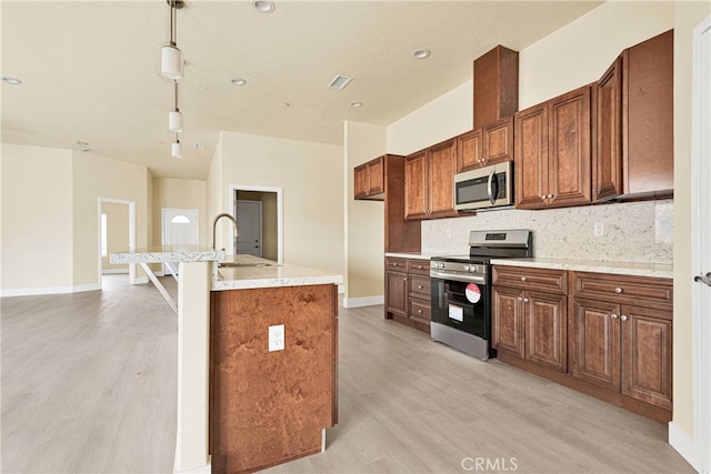 kitchen with appliances with stainless steel finishes, tasteful backsplash, pendant lighting, light wood-type flooring, and sink