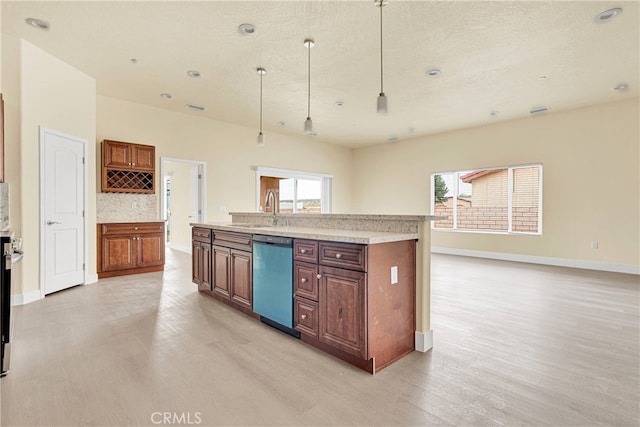 kitchen with light wood-type flooring, hanging light fixtures, dishwasher, and sink