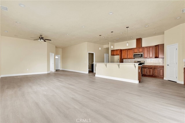 kitchen with a breakfast bar, a kitchen island, light hardwood / wood-style flooring, stainless steel appliances, and decorative light fixtures