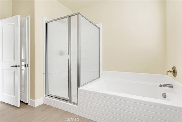 bathroom featuring plus walk in shower and wood-type flooring