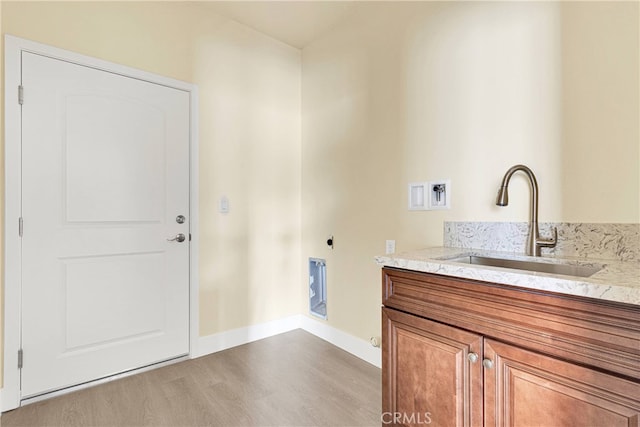 washroom with washer hookup, hookup for an electric dryer, light wood-type flooring, cabinets, and sink