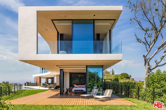 rear view of property featuring a balcony and an outdoor living space