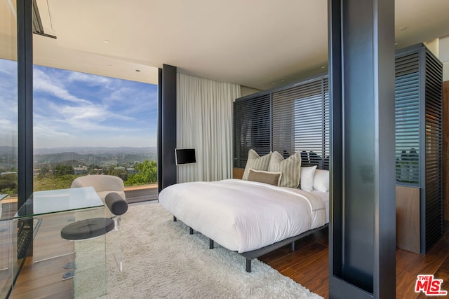 bedroom featuring expansive windows, a mountain view, and dark wood-type flooring