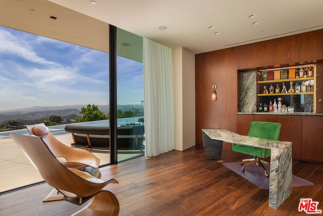 interior space featuring a wall of windows, wood walls, dark hardwood / wood-style flooring, and a mountain view