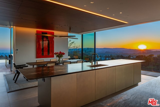 kitchen featuring a wall of windows, a large island with sink, sink, and a mountain view