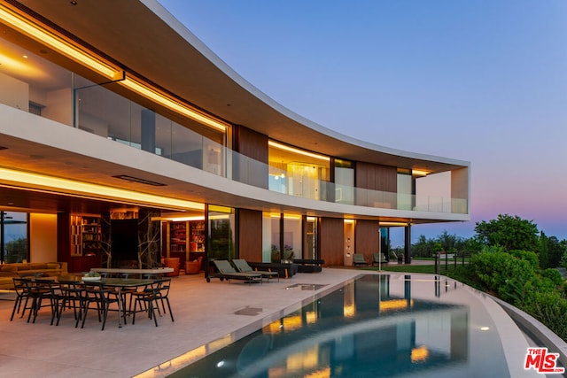 back house at dusk featuring a patio area