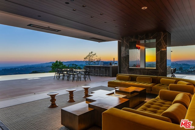 patio terrace at dusk with a water and mountain view and outdoor lounge area