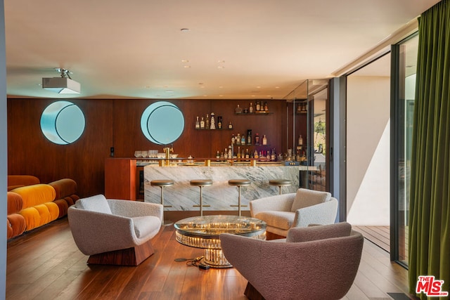 living room featuring wood walls, bar, and hardwood / wood-style floors