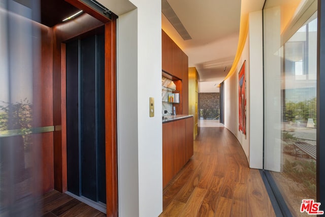 corridor with hardwood / wood-style flooring and elevator