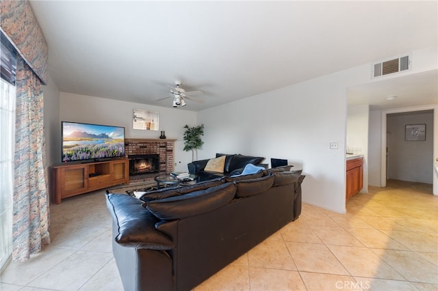 living room featuring light tile patterned floors, a brick fireplace, and ceiling fan