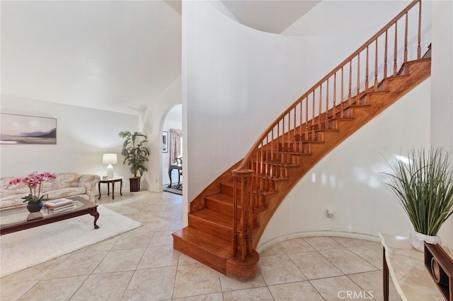 staircase featuring tile patterned flooring and high vaulted ceiling