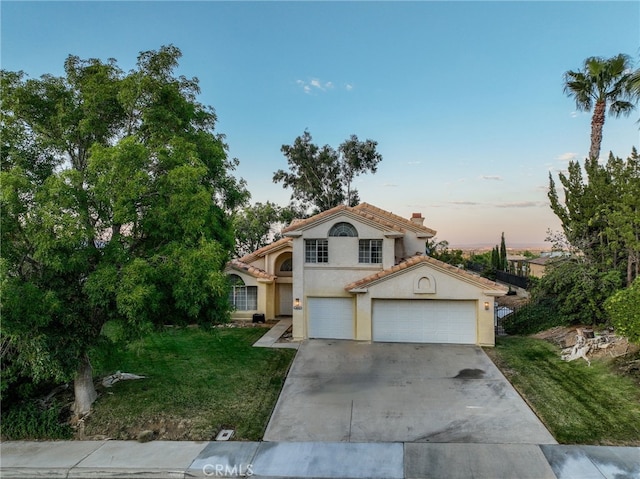 mediterranean / spanish-style home with a lawn and a garage