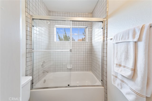 bathroom with toilet and shower / bath combination with glass door