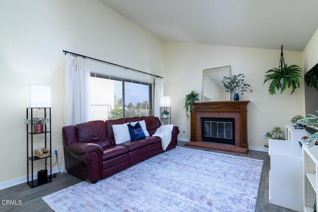 living room featuring dark wood-type flooring, vaulted ceiling, and a brick fireplace