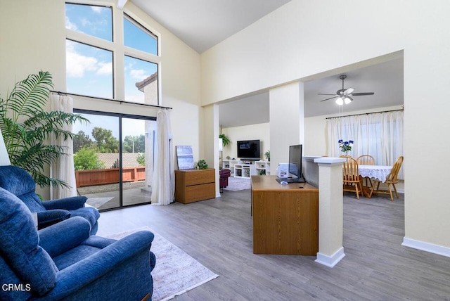 living room featuring ceiling fan, a healthy amount of sunlight, wood-type flooring, and high vaulted ceiling