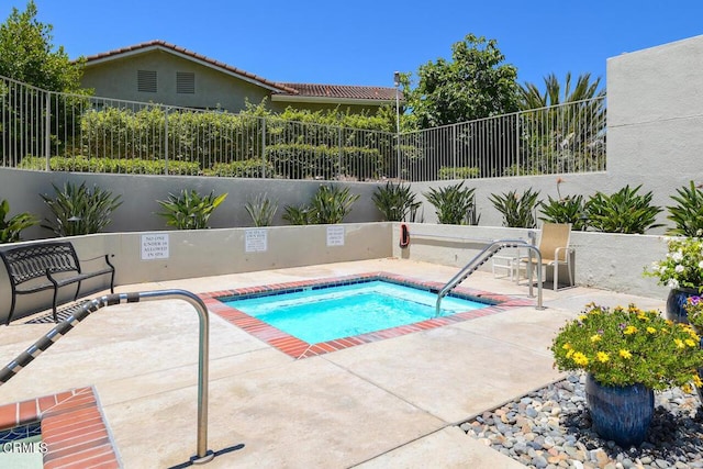 view of swimming pool featuring a hot tub and a patio area