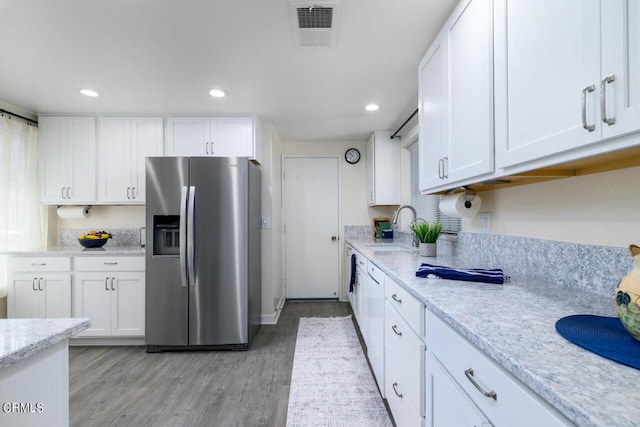 kitchen featuring white cabinets, sink, stainless steel refrigerator with ice dispenser, light hardwood / wood-style flooring, and light stone counters