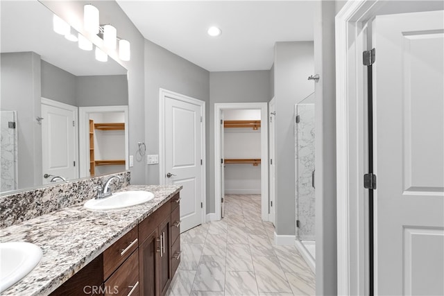 bathroom featuring a shower with door and vanity