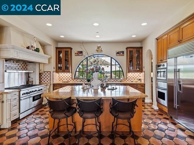 kitchen with premium appliances, a kitchen island, premium range hood, and tasteful backsplash