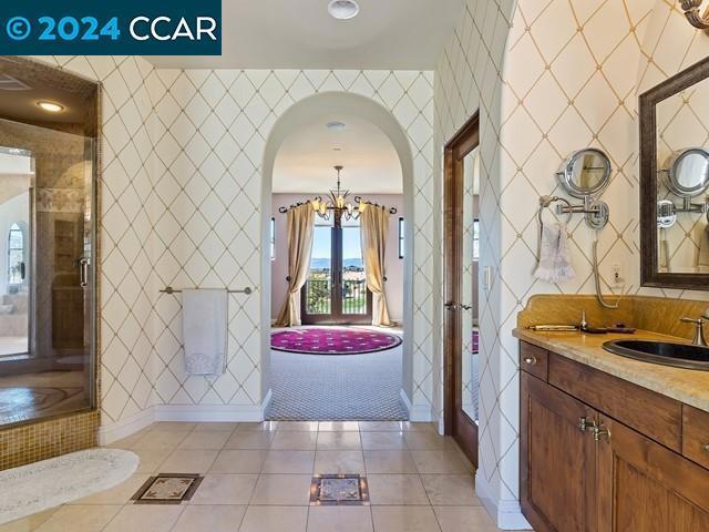 bathroom featuring tile patterned floors, vanity, a chandelier, and walk in shower