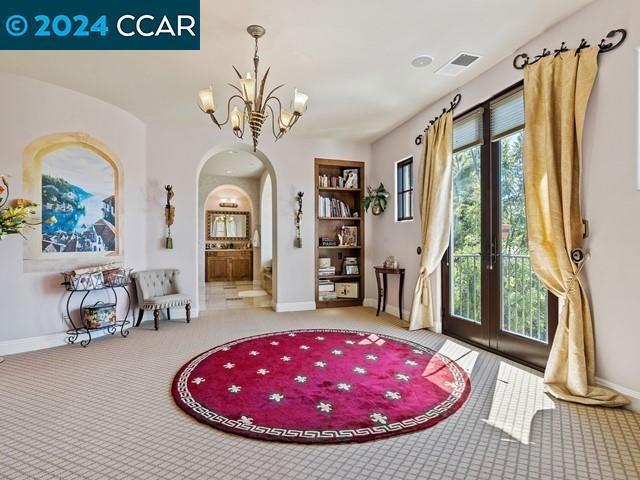 sitting room featuring a chandelier, french doors, and light colored carpet