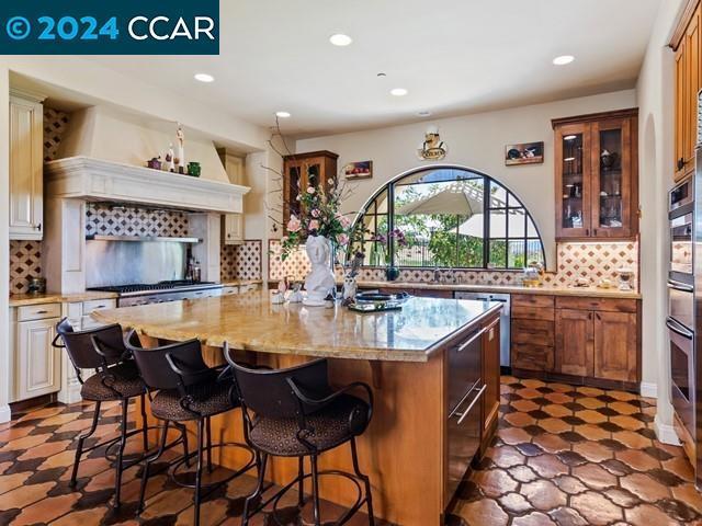 kitchen with a large island, a kitchen bar, stainless steel appliances, and tasteful backsplash