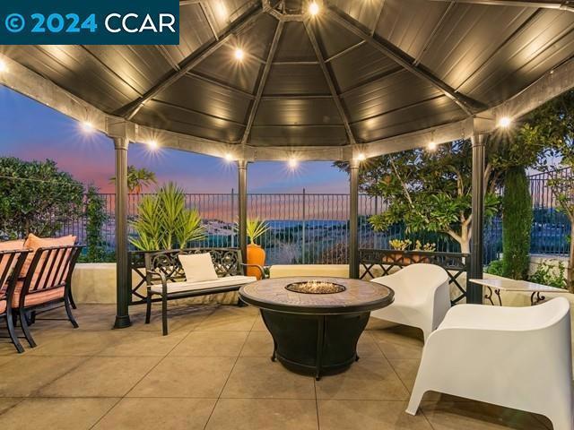 patio terrace at dusk featuring a gazebo and a fire pit