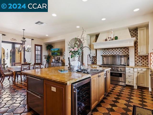 kitchen with backsplash, premium range hood, wine cooler, decorative light fixtures, and a kitchen island