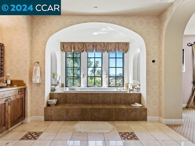 bathroom featuring vanity, a relaxing tiled tub, and tile patterned floors