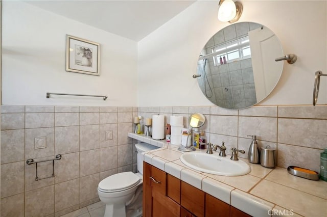 bathroom featuring vanity, tile patterned floors, tile walls, and toilet