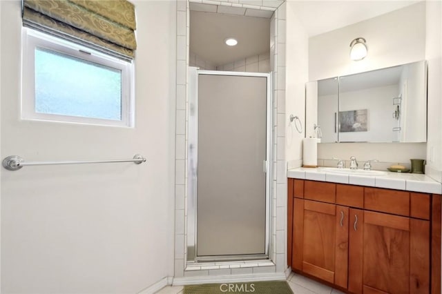 bathroom with tile patterned flooring, vanity, and walk in shower