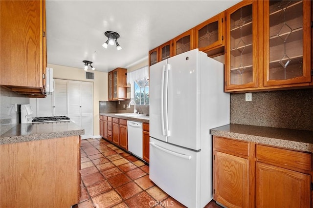 kitchen featuring decorative backsplash, white appliances, and sink