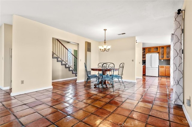 dining space with dark tile patterned floors and a notable chandelier