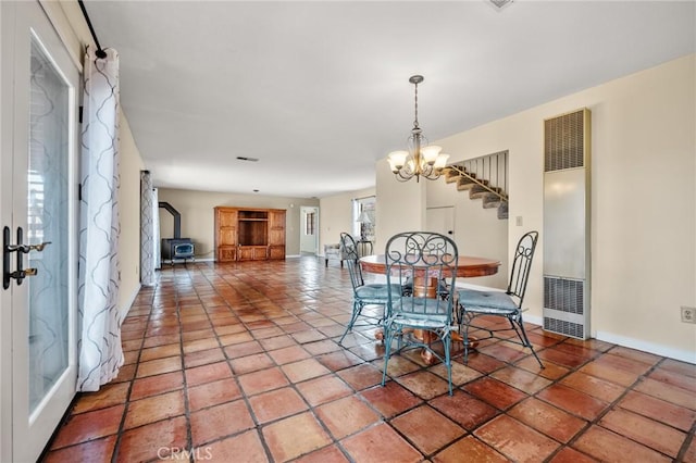 dining area with tile patterned flooring, a wood stove, and a chandelier